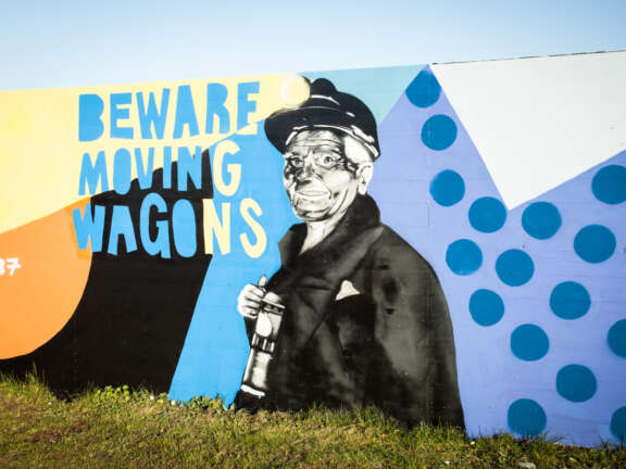 A section of a mural, designed to depict Dover's mining history. On it is a man with coal smeared across his face, with text that reads "Beware, moving wagons"