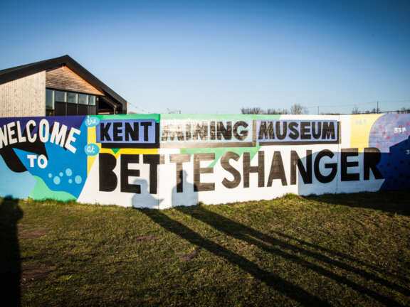 A section of a mural designed to represent Dover's mining history. The text painted onto the wall reads "Welcome to Kent Mining Museum Betteshanger"