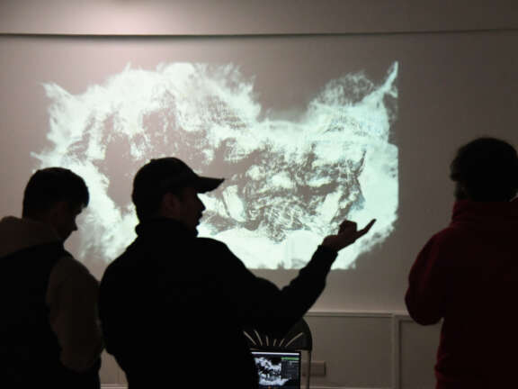People stand in a dark room with colourful projections on the wall