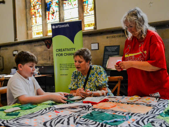 young people being assisted by two adults for craft making