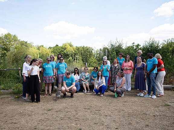 The Artswork team at their last staff away day, several members of the team are looking down at a Goose that has joined the group photo.