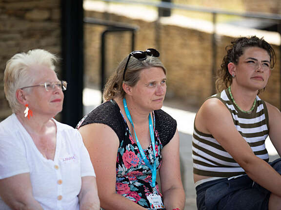 Three Artswork staff members looking up and listening intently to a facilitator (not in view) teaching them about cycle safety.
