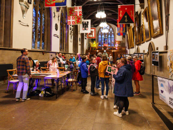 inside the Maison Dieu a historical building many people gathered enjoying the festival under flags and next to tables with craft activities