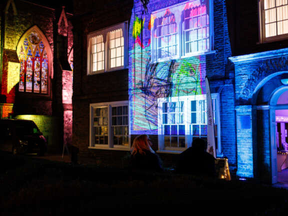 A building that has been illuminated with multicoloured projections of young people's artworks