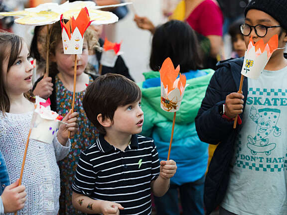 Three young people holding paper cup Diwali lanterns they made for a Diwali parade