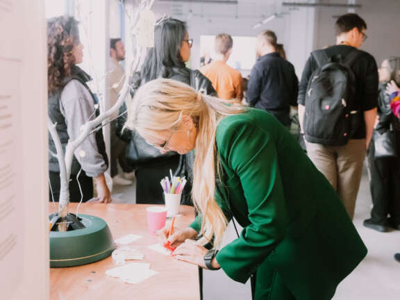A woman writes on a tag ready to hang it on the 'wishing tree'.