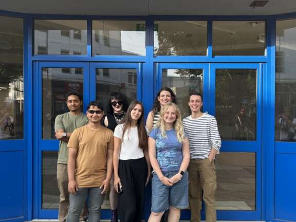 7 people stand outside Playland with the 'Playland' sign in view