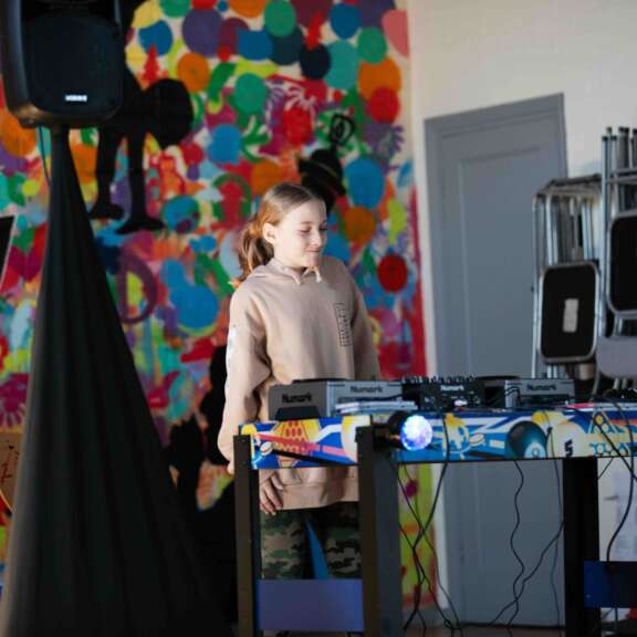 Young girl standing in front of sound equipment