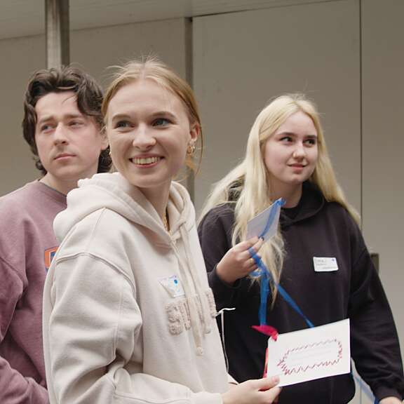 4 young people in casual clothing in a candid shot, person at forefront smiling at something off camera