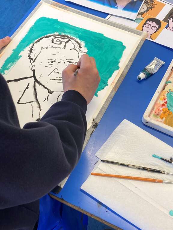 close up of someones hand painting colour on a line drawing of person