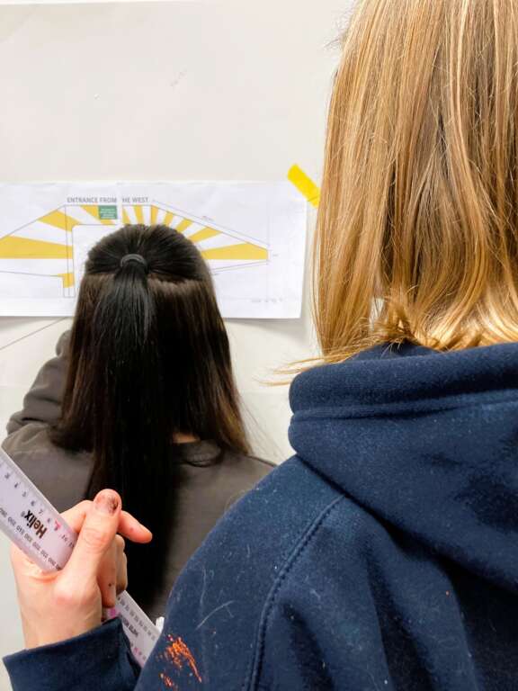 two young girls looking at a design of a mural