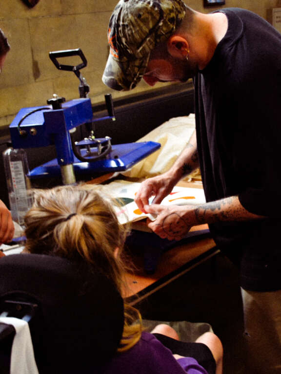 young person being assisted by an adult in print making