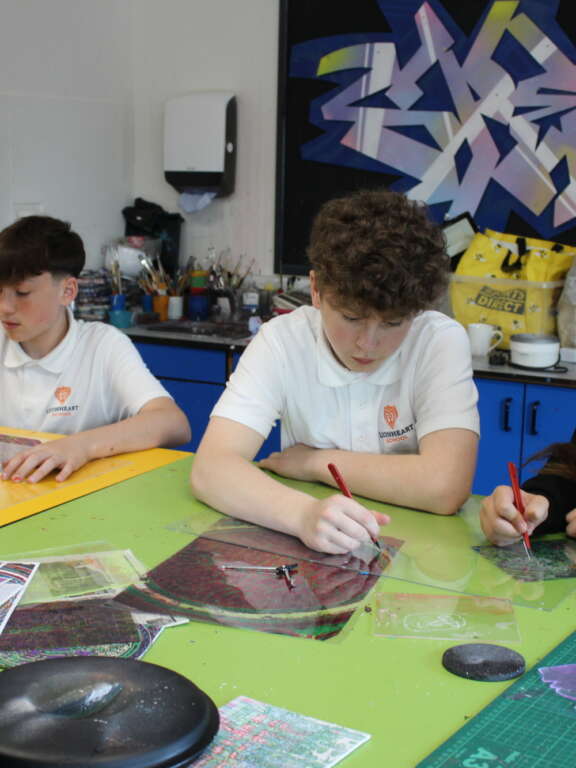 Three secondary age pupils etching on plastic