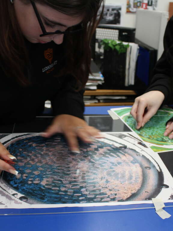 Two young people etching on clear plastic over circular abstract art designs