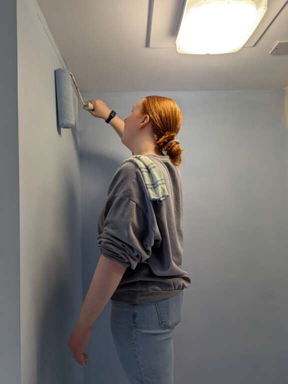 Young person painting blue wall