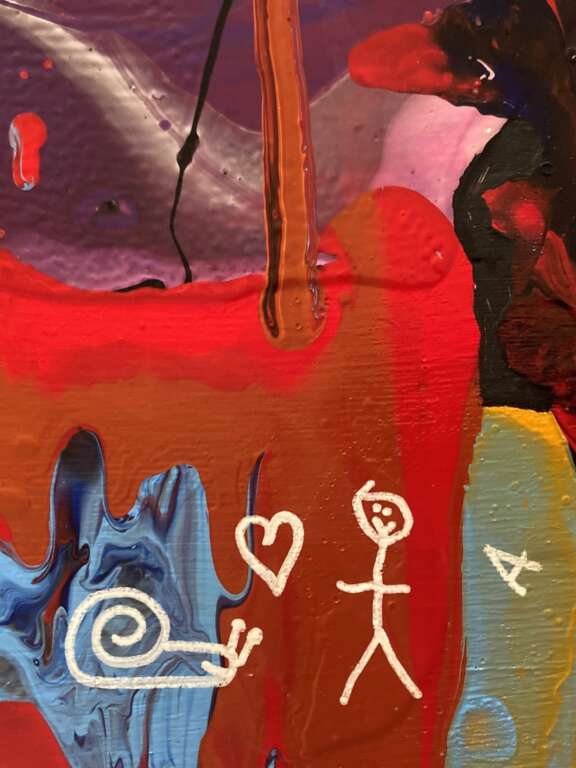 close up of paint pour artwork with a snail, stick man, 'A' and two hearts drawn on as signatures in white pen