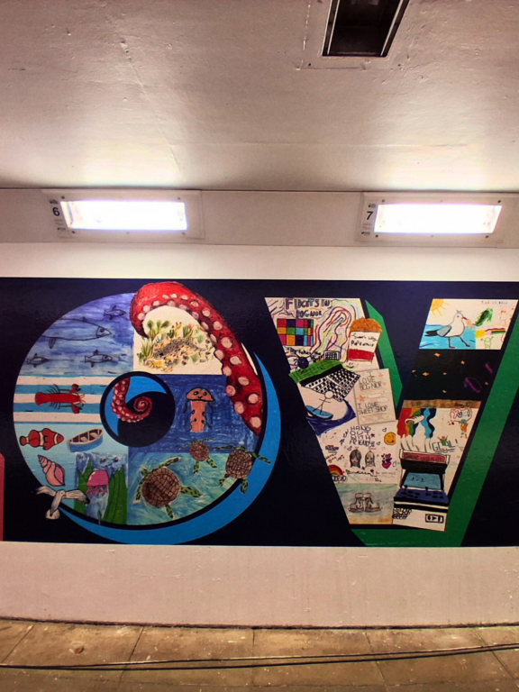 mural on wall of underpass - large letters that spell the word LOVE made up of lots of hand drawn images by children