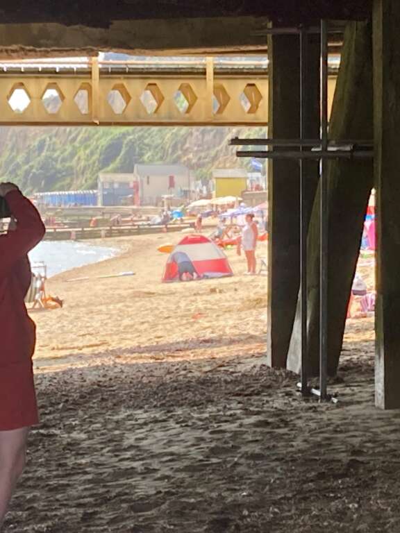 young person taking photo underneath a pier