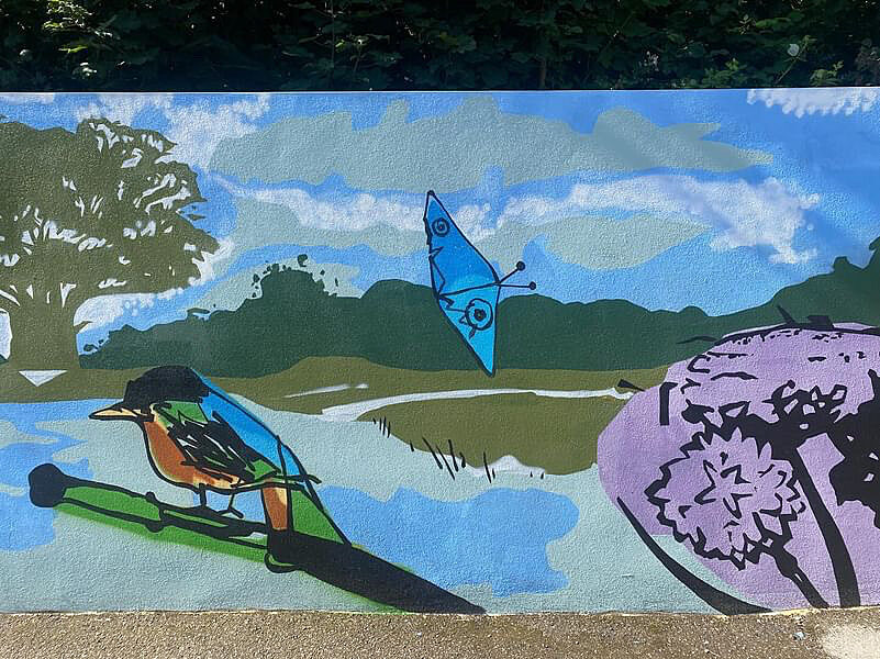 A section of a colourful mural with a bird, a blue butterfly and trees on it