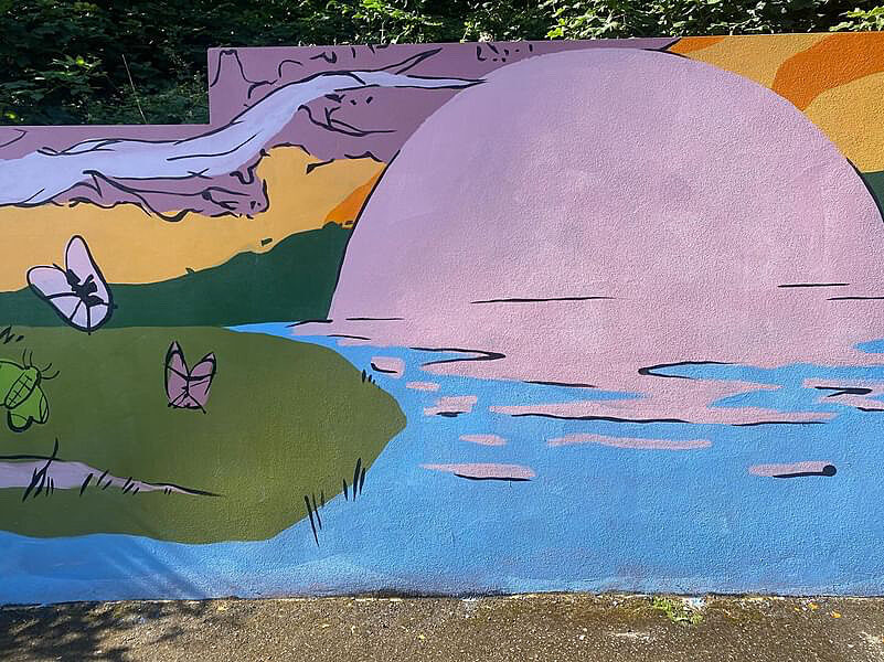 A section of a colourful mural that has a pink sunset on water, pink butterflies and an orange sky