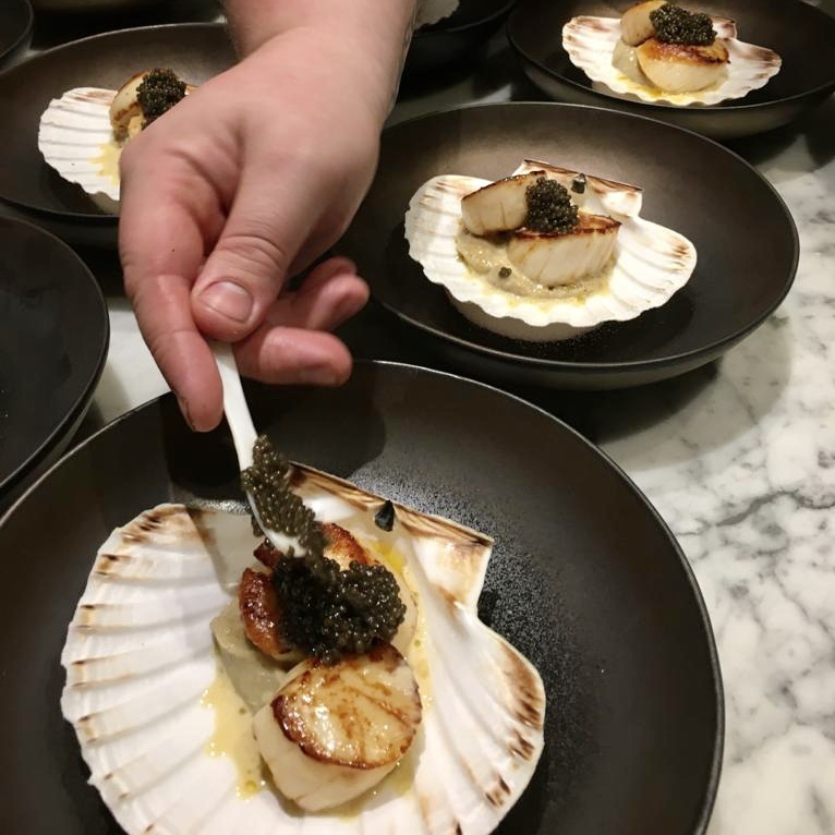 Chef putting caviar on a scallop