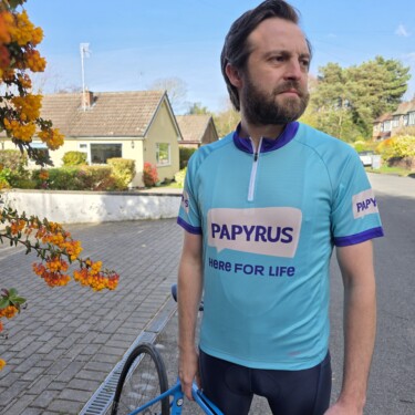 A cyclist standing next to a bike wearing a Papyrus cycling top