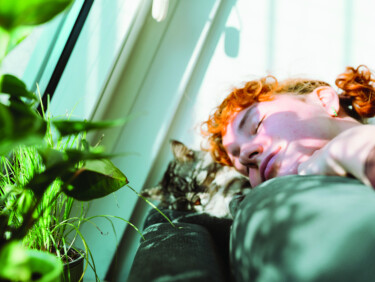 Girl with eyes closed near window with light coming in