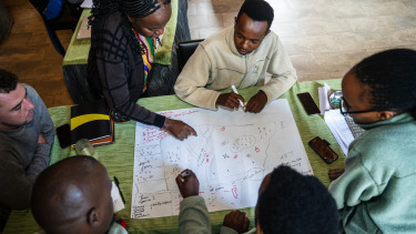 A group of people sit at a table looking at a hand drawn map