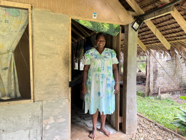 A woman in a blue floral dress stands in the doorway of a building
