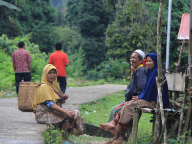 A group of people talking and laughing on the side of the road with a forest in the background