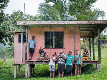 A group of men standing outside a wooden building painted pink