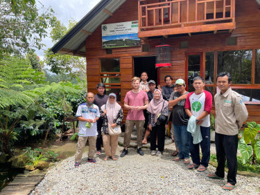 A group of people stand on a gravel path in the sunlight