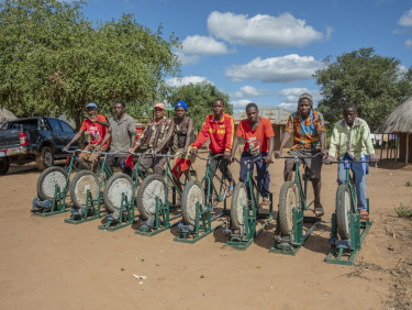 A row of men all sitting on bicycles which are part of an irrigation apparatus
