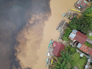A drone shot of a settlement on the edge of a riverbank