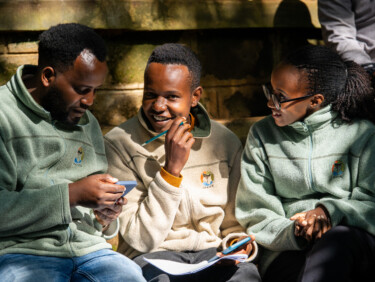 Two men and a woman sit next to one another talking