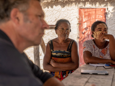 Two women sitting at a table with a white wall behind them