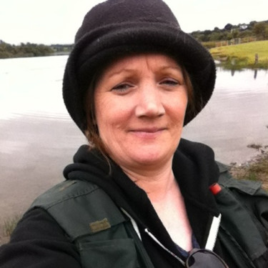 A woman in a black hat standing in front of a body of water