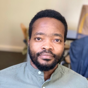 A man in a grey shirt in front of a beige wall
