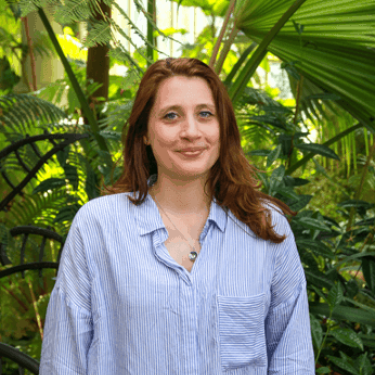 A woman in a blue shirt stands in a forest