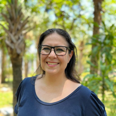A woman in a navy t-shirt stands in a forest