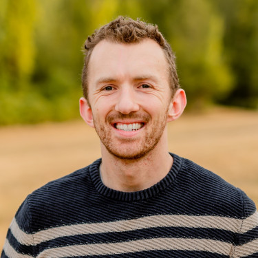 A man in a stripy jumper smiles on a beach