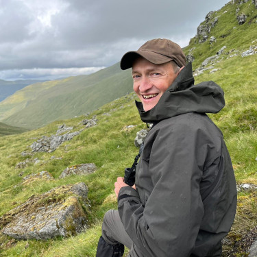 A man in a black anorak in a mountainous landscape