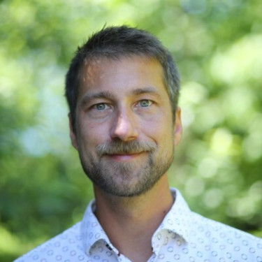 A man in a white shirt in a forested area
