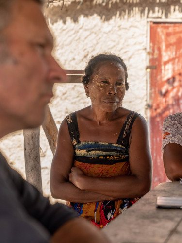 Two women sitting at a table with a white wall behind them
