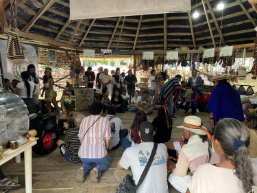 A group of women and men gather in a maloca hut