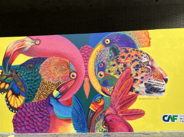 Bright and vibrant street art of a flamingo, tiger and birds in pinks and yellows