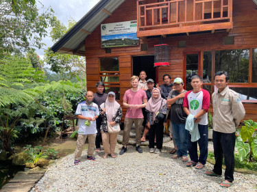 A group of people stand on a gravel path in the sunlight