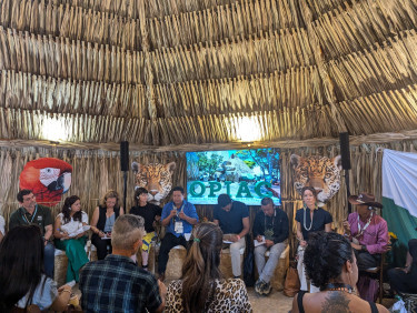 A group of women and men gather in a maloca hut