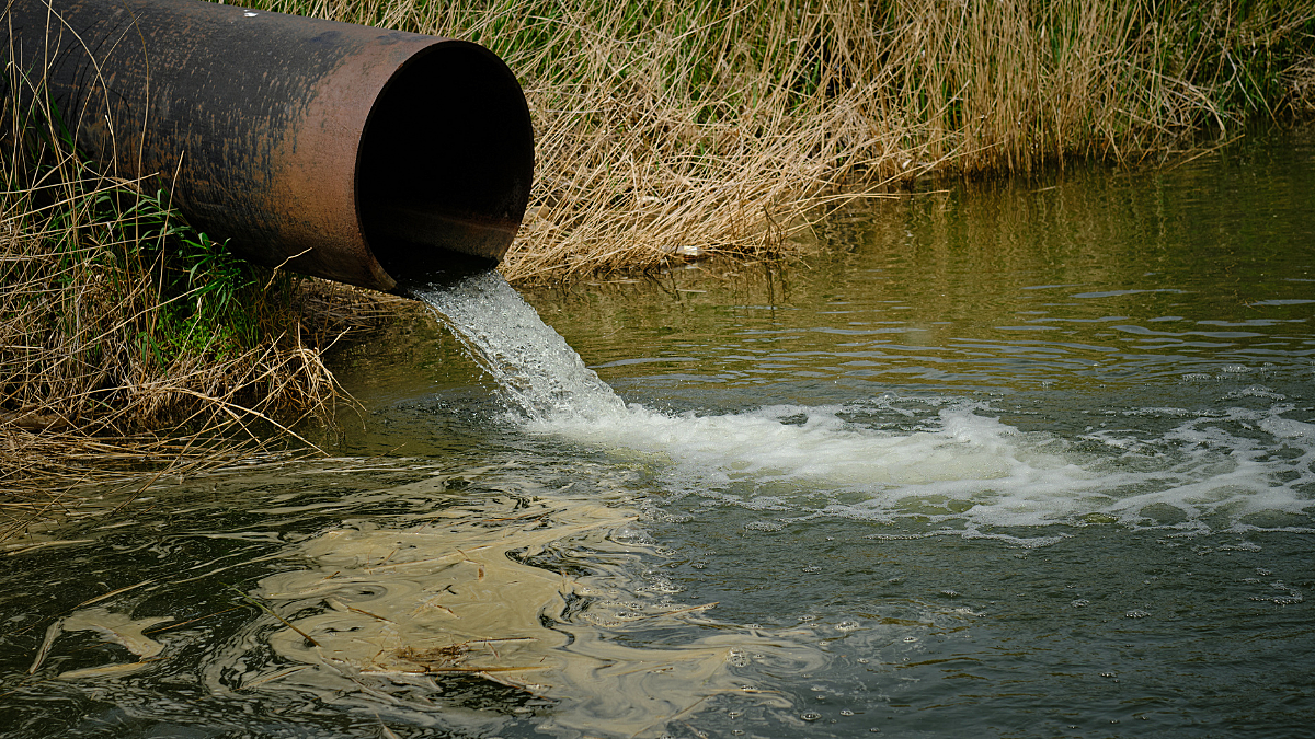 Pipe overhanging a river with water pouring out into river