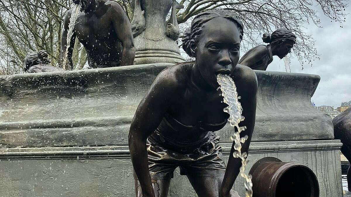 A bronze statue of a girl bent over, with water flowing from her mouth as if being sick, highlighting the issue of sewage in watercourses
